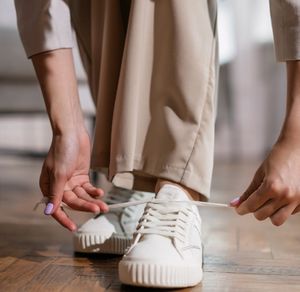 A person tying shoelaces on training sneakers.